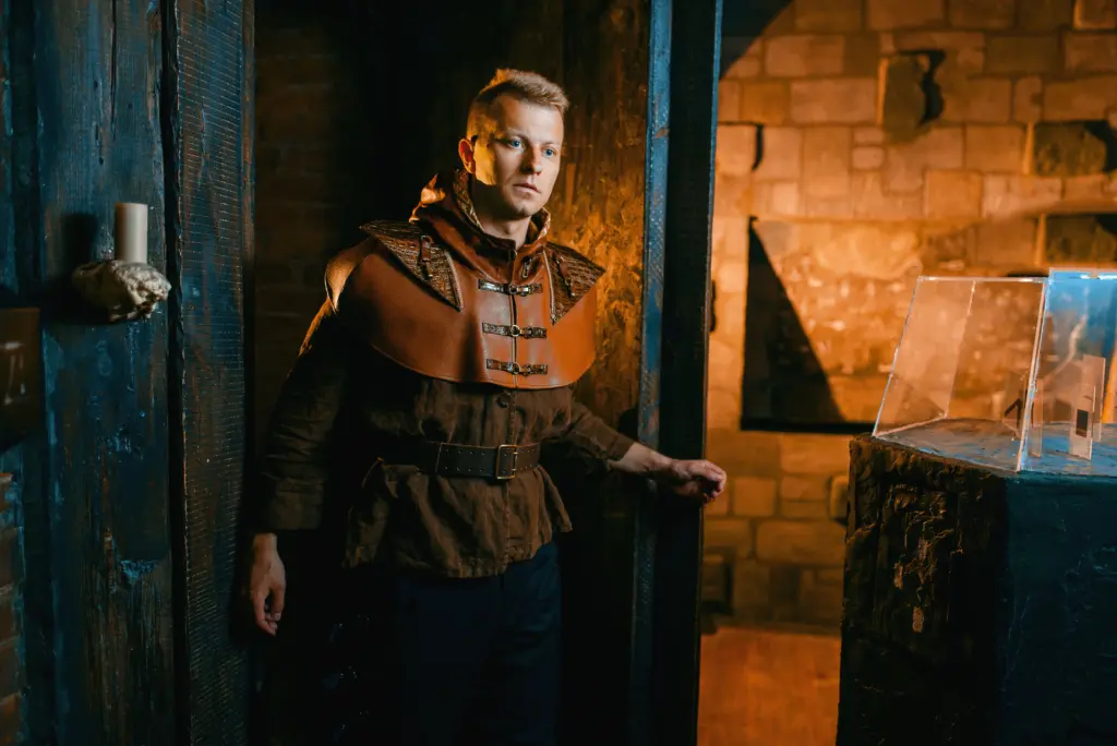 A man dressed in ancient-style clothes enters a prison dungeon through a door.
