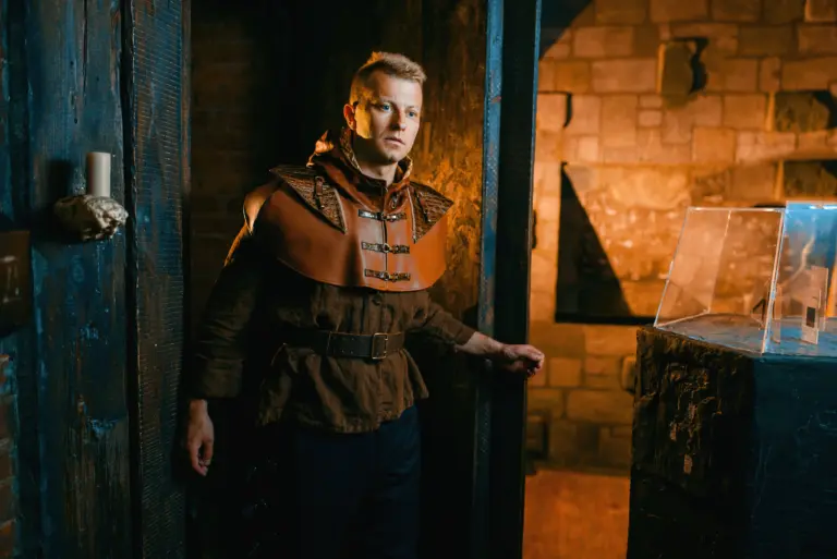 A man dressed in ancient-style clothes enters a prison dungeon through a door.